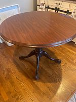 Full view of the assembled round table showing wood top and pedestal base on wood floor