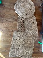 Photo showing the three mats arranged on the floor: rectangular, oval and round mats woven from wicker and straw materials.
