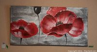 Front view of oil painting on canvas showing two large red flowers with textured black and white background and inner wood frame support.