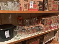 Shelf with black enamel pot and glass jars alongside boxes of Bernardin lids and mason jars