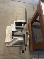 Mastercraft MC3000 electric chain saw placed on a small white stool for display on a concrete floor near wooden furniture.