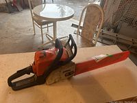 Chainsaw on workbench with orange protective bar scabbard installed