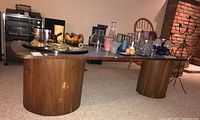 Side view of the coffee table showing tabletop with decor items and cylindrical wood veneer base with chipping and scratches.