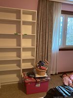 Full view of the white melamine shelving unit placed near a window in a room. Adjustable shelves visible.