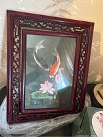 Framed rotating art piece showing two koi fish and lotus flowers inside a carved wooden frame.