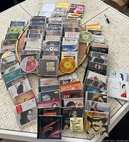 Collection of various music CDs arranged on table, showing multiple titles and jewel cases.