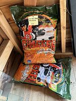 Two 20L bags of organic chicken manure stacked in a garden shed with a note on top identifying them.
