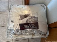 Photo showing the comforter set in packaging, labeled as full/queen size and 5-piece set including comforter, shams, and cushions.