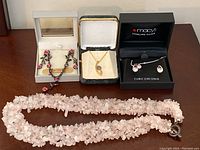 Group photo showing multiple pieces of jewelry including long pink chip bead necklace, two boxed sets of earrings with matching necklaces, and gold-tone necklace with blue stone pendant.