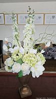 Full front view of faux flower arrangement in planter showing white roses, light green hydrangeas and tall white blossoms with curly green stems