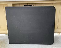 Top view of the closed black folding table showing its rectangular shape and surface condition.
