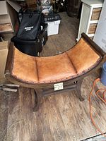 Front angle displaying the full leather seat and wooden frame shape.