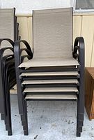 Stack of five patio chairs with metal frame and beige woven material seats and backrests.