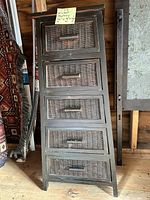 Full view of the shelving unit showing five wicker drawers and dark wood frame