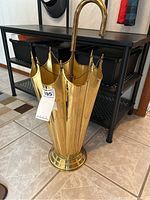 Full frontal view of the brass tone umbrella stand showing its umbrella-like design with a handle hook and tiered base.