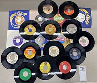 Spread of 20 various 45 RPM vinyl records showing multiple labels and some sleeve covers.