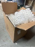 Large cardboard box filled with multiple shrink-wrapped packs of hexagonal white jewelry boxes, stacked inside.
