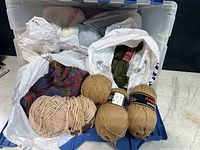 Full open bin showing yarn balls and skeins in plastic bags and loose within bin
