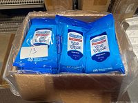 Box open showing multiple blue packs of Germ Out antibacterial wet wipes, each pack with 40 wipes and fresh scent.
