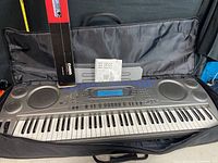 Casio WK-1800 keyboard inside padded nylon carry bag with user guide and stand packaging visible