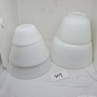 Two stacks of white milk glass and ribbed mixing bowls on a white surface, showing the smooth and ribbed textures.