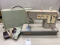 Singer Zig-Zag Model 457 sewing machine with gray carrying case, foot pedal, and accessories on a table.