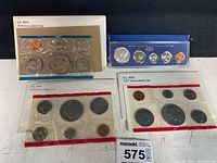 Four uncirculated coin sets from the U.S. Mint, years 1966, 1975, 1977, and 1978 displayed on a white surface.