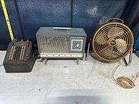 Corona adding machine, Markell heater, and Frigid fan side by side on a table