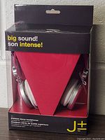 Front view of boxed J+ premium stereo headphones showing the headphones and branding