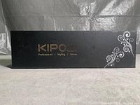 Closed black carry case with gold Kipozi branding and white swirl design