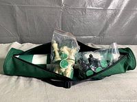 Zippered carry case opened showing two plastic zip bags, one with white chess pieces, one with black chess pieces with green felt bottoms.