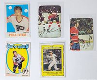 Five NHL and MLB trading cards displayed face up showing player images and teams: Bobby Clarke, Lew Morrison, Reggie Leach, Larry Robinson, and Roberto Clemente.