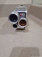 Front view of the 1950s Kodak Brownie movie camera showing three circular lenses/apertures of different sizes and part of the metallic body.