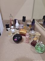 Wide view of 21 assorted partial perfume bottles on a bathroom countertop, mixed shapes and colors visible