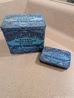 Two Edgeworth pipe tobacco tins, one large square and one small rectangular, blue color with text and decoration.