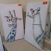 Two canvas art pieces displayed side by side showing giraffe portraits on white background, with price tags and protective corners.