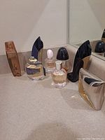 Eight partially full assorted perfume bottles placed on a counter, some without lids