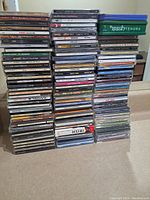 Photo of four stacks of assorted music CD jewel cases, showing spines with artist and album titles