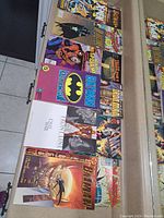 Photo showing an assortment of superhero comic books including Batman, Spider-Man, X-Men, and others laid out flat with visible cover art.