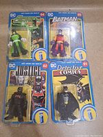 Four Imaginext DC Superfriends 80th Anniversary action figures in original unopened packaging arranged on floor, card numbers visible.