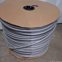 Full large spool of tightly coiled gray closed cell backer rod, showing side view of spool with rod wound around cardboard core.