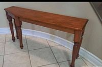 Front and side views of the solid wood narrow low table showing the unique shape of the tabletop and turned legs.