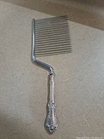 Front view of the sterling silver vintage cake cutter showing the handle design and prongs.