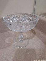 Side view of the crystal pedestal bowl showing pinwheel and starburst cut patterns with scalloped rim and clear pedestal base.
