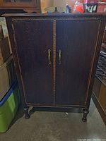 Front view of vintage wooden cupboard with closed double doors and metal handles
