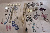Full view of assorted vintage jewelry arranged on flat surface including bracelets, earrings, necklaces, and brooches.