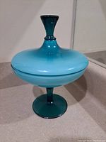 Front view of vintage blue glass pedestal dish with lid showing overall shape and colors