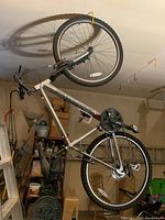 Diamondback mountain bike hanging from ceiling hooks in garage. Visible full bike frame, tires, handlebars, and seat.