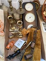 Overview showing brass candle sticks, brass barometer set, brass owl, ceramic dog, decorative bells, and other figurines.