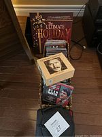 Photo showing basket of assorted CDs and cassette tapes with holiday songbook and Gordon Lightfoot songbook visible on top.